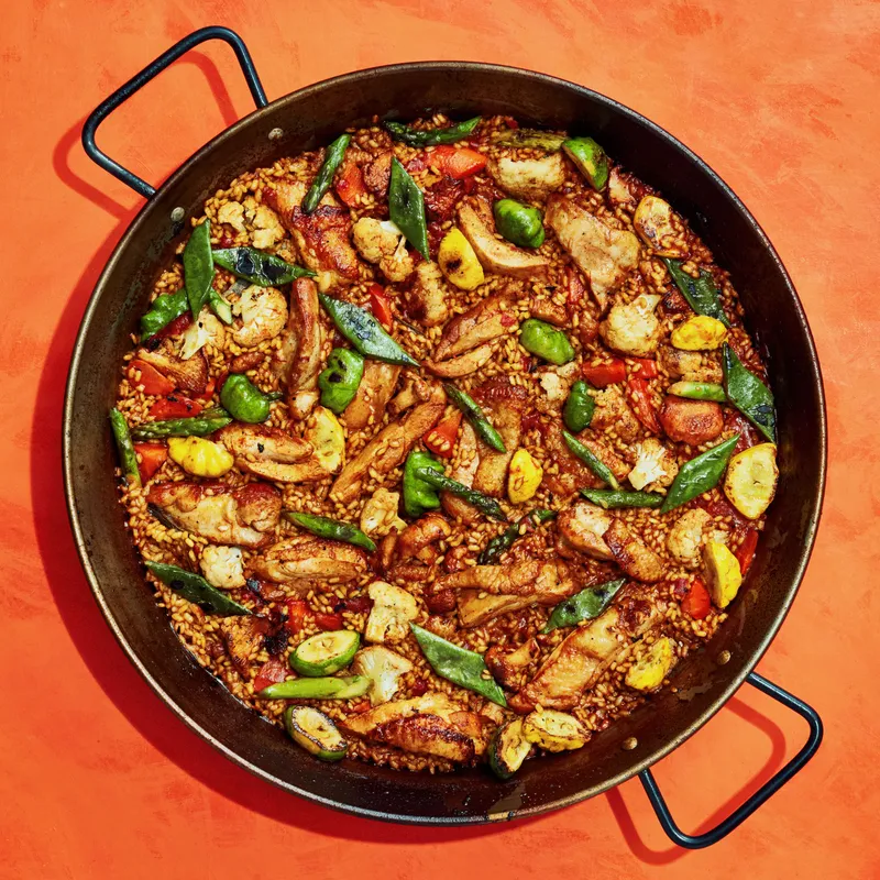 Skin-on chicken thighs, chanterelles, pattypan squash, carrots, cauliflower, romano beans, asparagus, paprika, grated tomatoes, saffron, chicken stock, rosemary, and Bomba rice cooked in a paella.