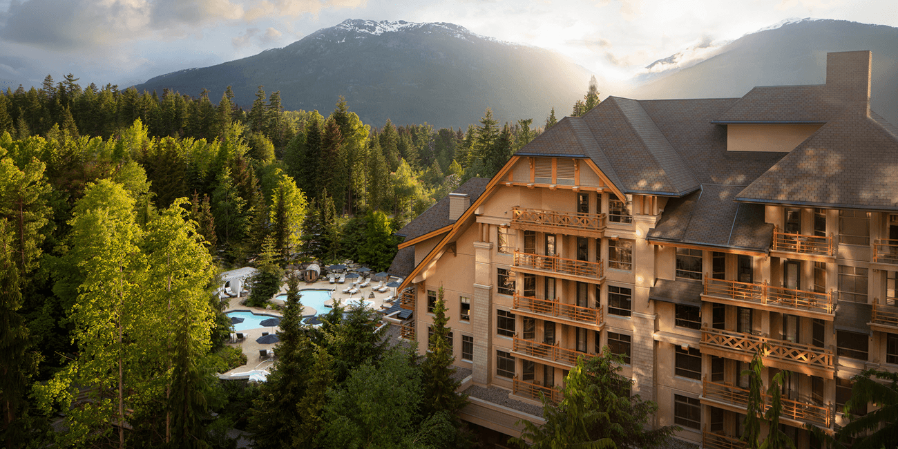 Mountain resort with a pool surrounded by lush trees and mountains.