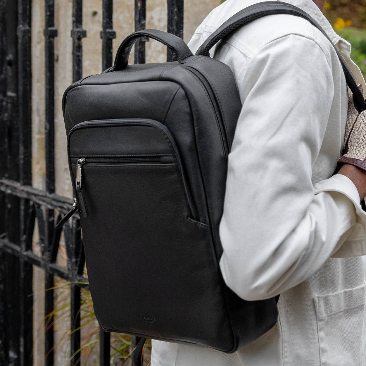 Man carrying a black leather backpack on a walk