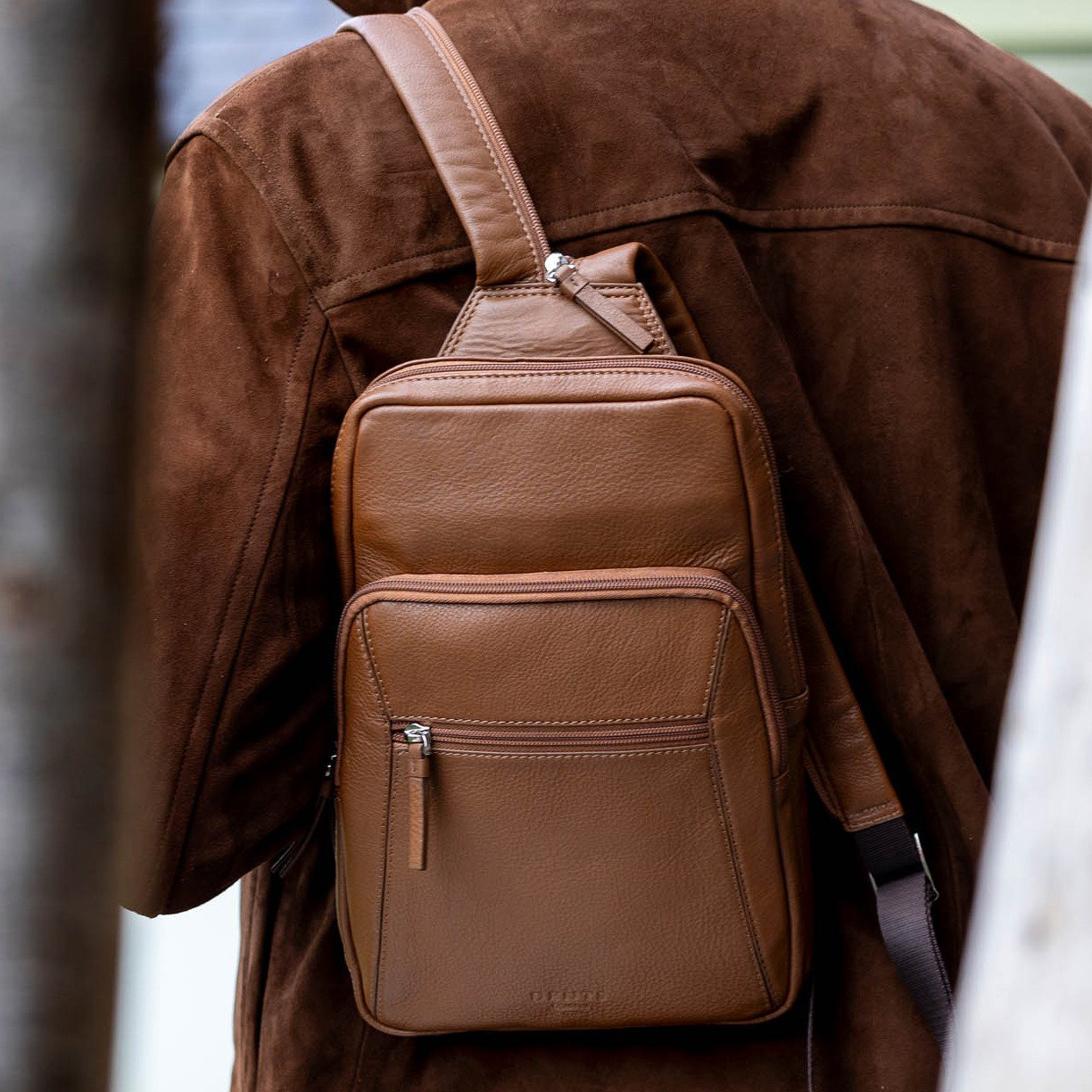 Man carrying a small backpack in caramel on a walk