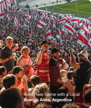 A crowded soccer stadium filled with fans waving red and white flags.
