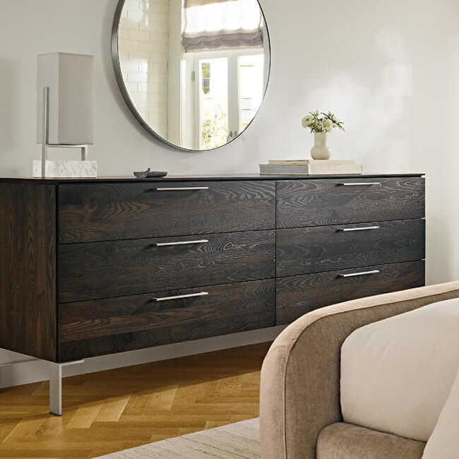 Kenwood bedroom dresser with dark wood grain, six drawers and metal base beneath a round mirror.