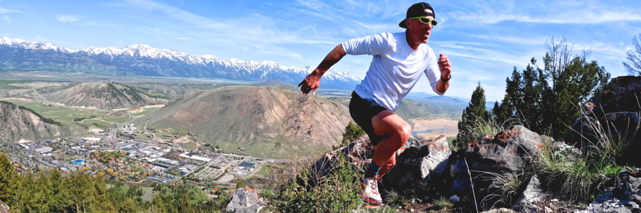 Person running up a mountain with a valley behind them