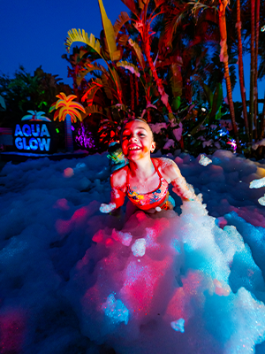 A young child playing with bubbles during AquaGlow at Adventure Island
