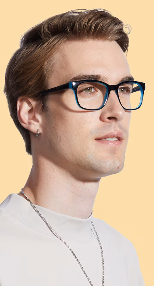 Man with brown hair and a silver earring, wearing two-tone black and blue rectangular glasses, against a light yellow background
