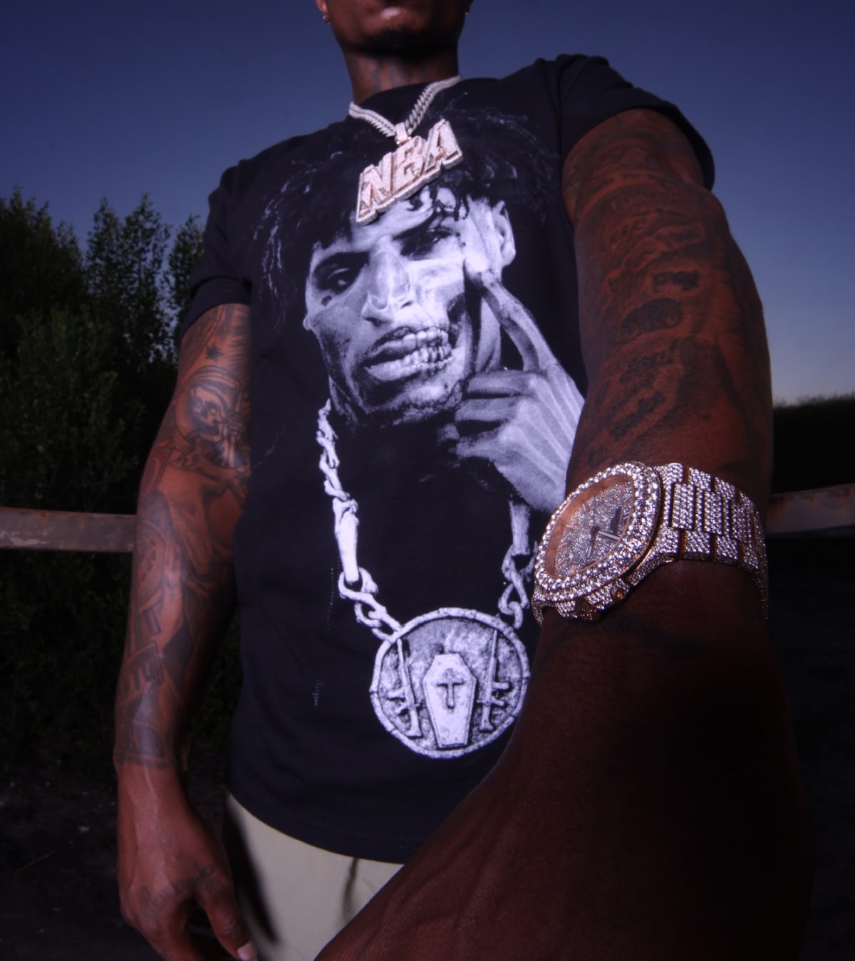Shop NBA YoungBoy | Zoomed-in image of the rapper wearing a graphic tee of his own face, tracing his teardrop tattoo.