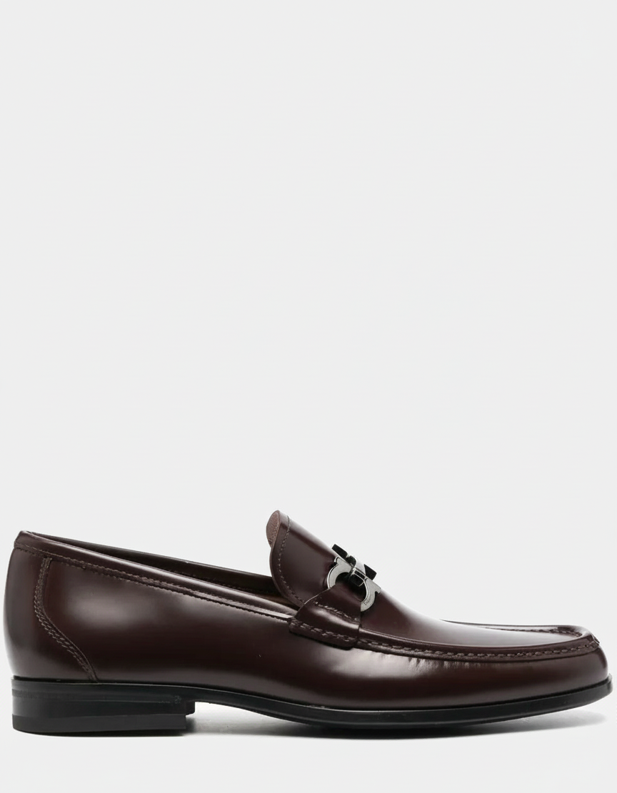 A brown leather loafer with a silver buckle.