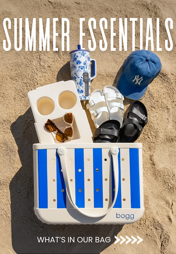 Summer Essentials. See what's in our bag. Image of a blue striped Bogg Bag with Birkenstock sandals, a '47 hat, two pairs of Goodr sunglasses, and a Brumate water bottle.