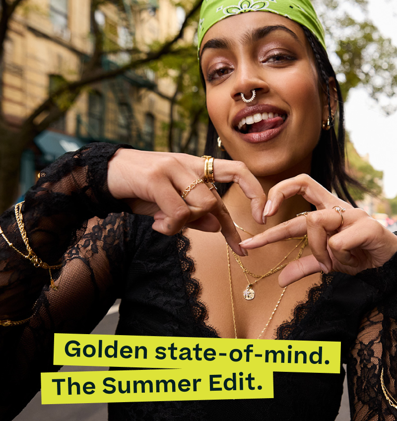 Model layered in gold jewelry, including multiple necklaces with charms, rings and bracelets. Golden state-of-mind. The Summer Edit.