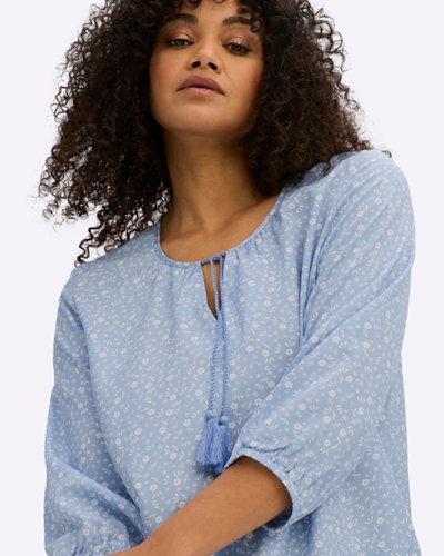 Model mit hellblauer Tunika mit weißen Millefleurs-Blümchen