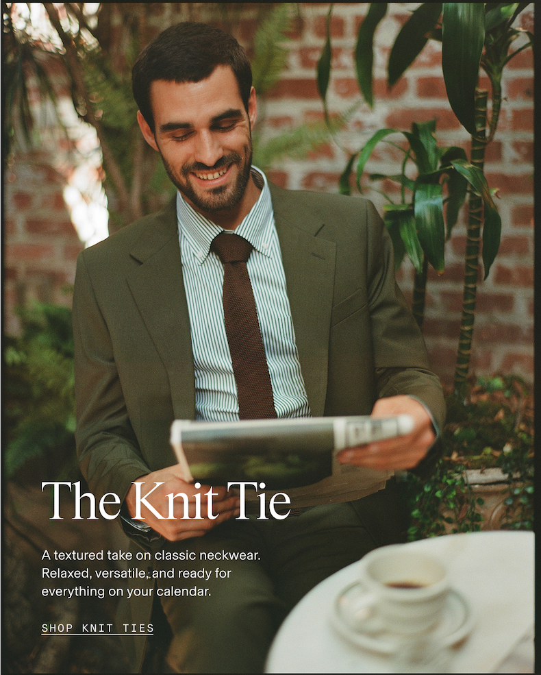 Man in an olive suit and striped dress shirt wearing a brown knit tie, smiling while reading a magazine outdoors in a garden setting. "The Knit Tie" "A textured take on classic neckwear. Relaxed, versatile, and ready for everything on your calendar." "SHOP KNIT TIES"