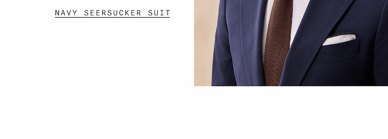 Close-up of a navy seersucker suit jacket lapel with a brown knit tie and white pocket square. "NAVY SEERSUCKER SUIT"