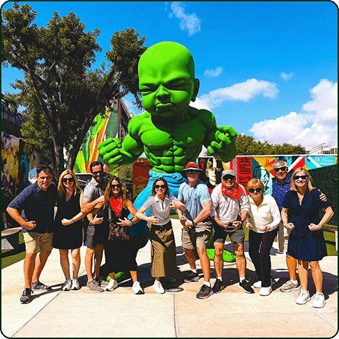 Image description: A tour group posing in front of a large statue of Baby Hulk