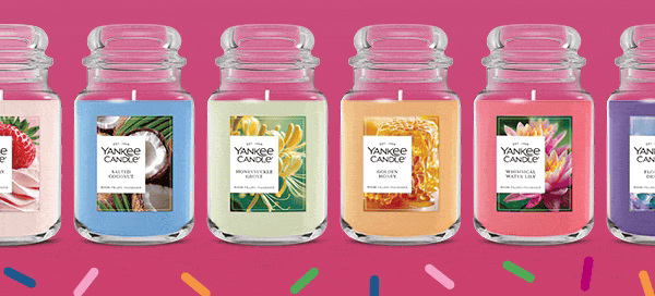 Six Yankee Candle jars in various colors and scents on a pink background with confetti graphics.