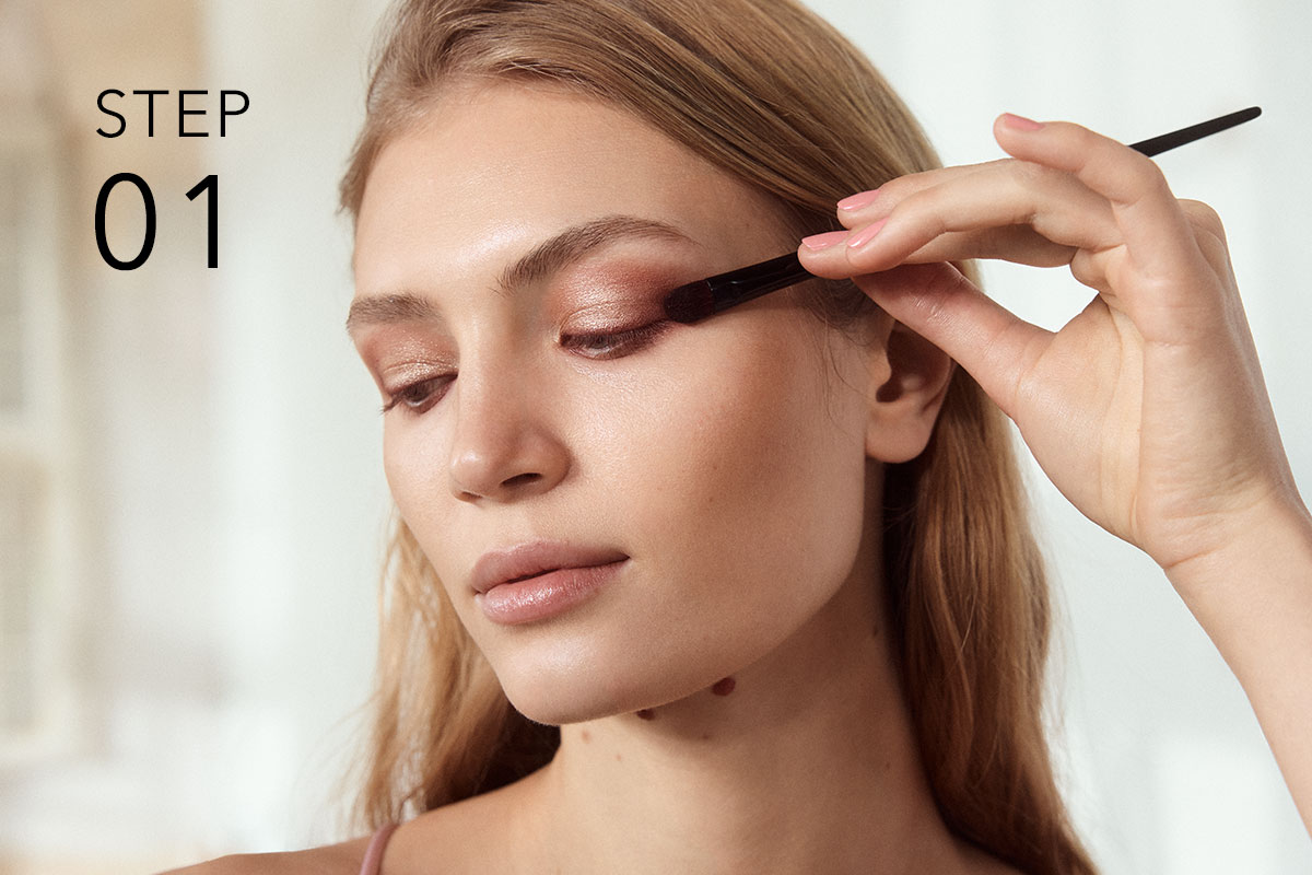 Beauty-Motiv mit „STEP 01“: Person trägt mit einem Pinsel Lidschatten auf.