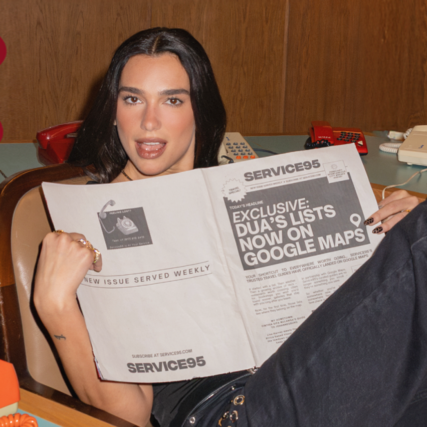 Dua Lipa in a retro office holding a newspaper