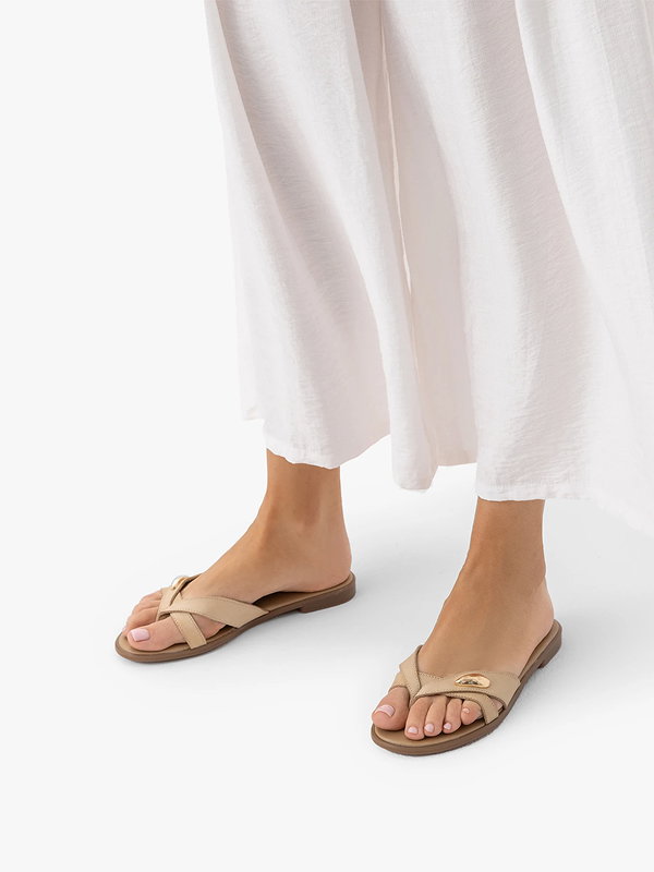 Woman wearing beige sandals and a white dress on a white background