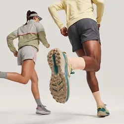 Dos personas con ropa deportiva y gorras corriendo hacia adelante sobre un fondo liso y claro.