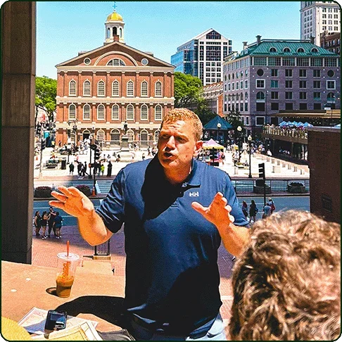 Image description: A tour guide speaking in front of Boston’s Faneuil Hall