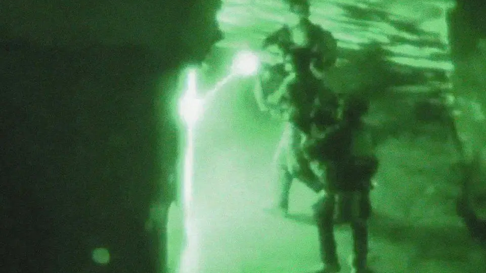 Three soldiers pictured in green night vision footage.