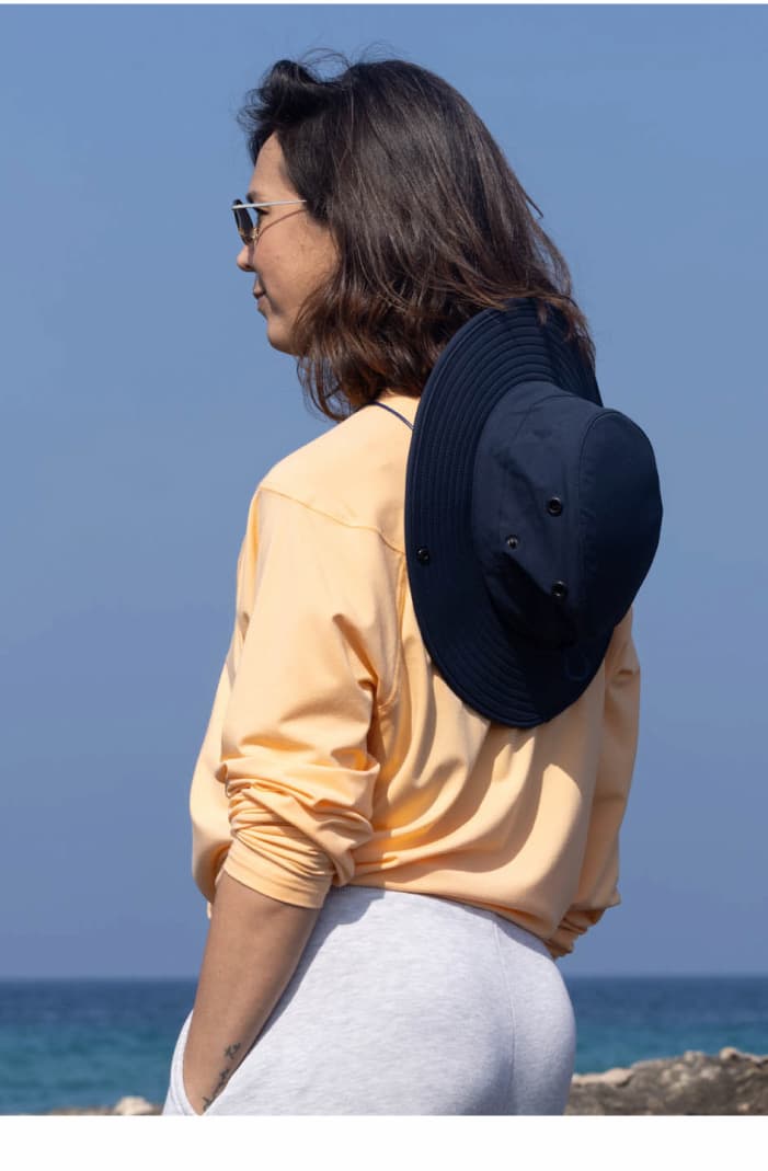Woman Wearing UPF 20+ Bamboo Sun Shirt in Canyon Glow and Trek All-Weather Hat in Navy/Steel Blue