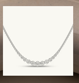 A white gold diamond tennis necklace with graduated stones in the center.
