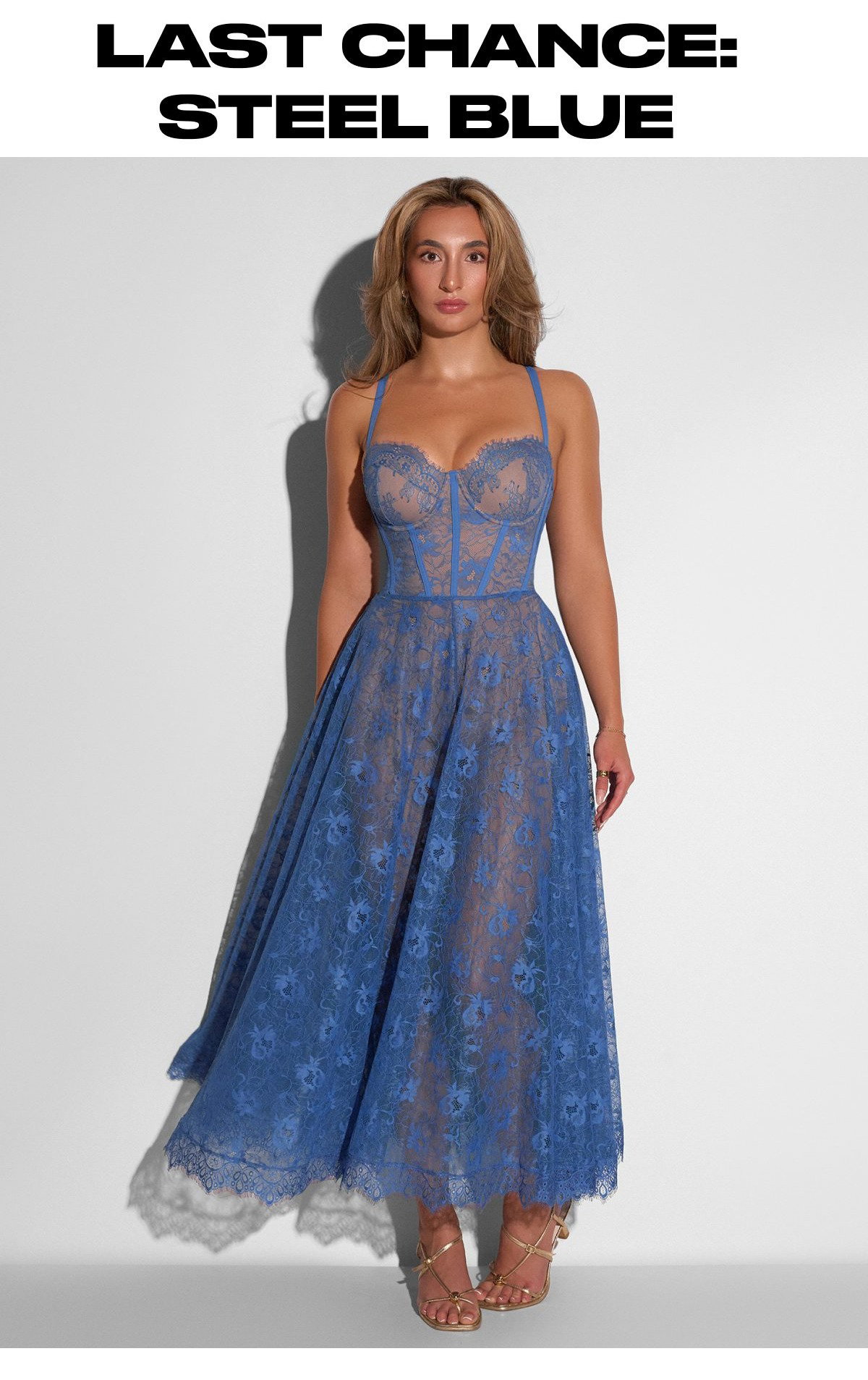 A woman wearing a steel blue lace midi dress with a fitted bodice and a flared skirt.