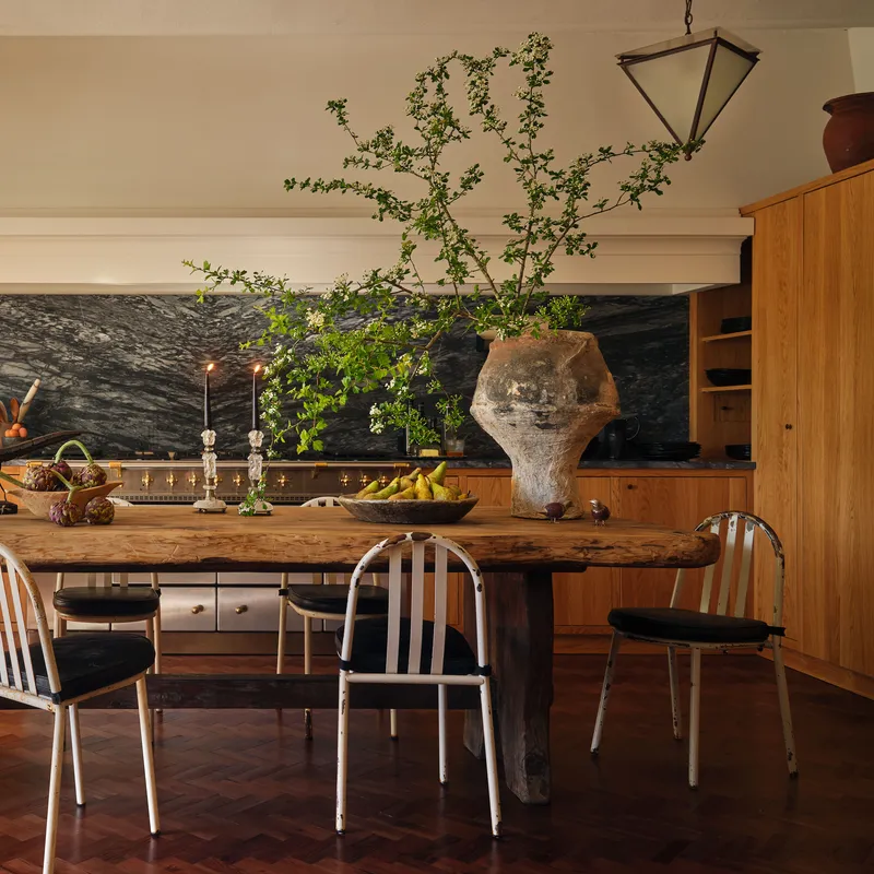  Kitchen with large wood table and dark backsplash behind it. 