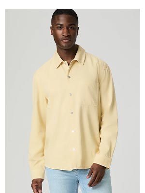 An image of a man wearing a butter yellow long sleeve button up top in lightweight denim.