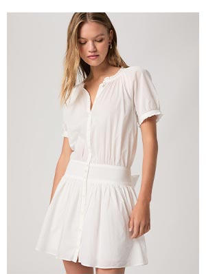 A woman wearing a white dress with dropped waist in a lightweight breathable cotton fabric.