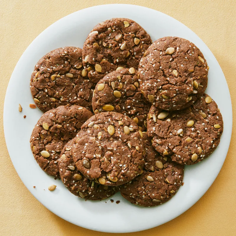 Grain-free almond butter cookies with sesame, pepitas, sunflower seeds, hemp seeds, and flax seeds on a plate.
