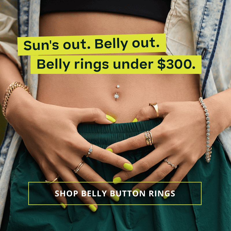Model’s midriff with diamond belly ring, rings & diverse bracelets. Sun’s & belly’s out. Belly rings under $300. Click here to shop belly button rings