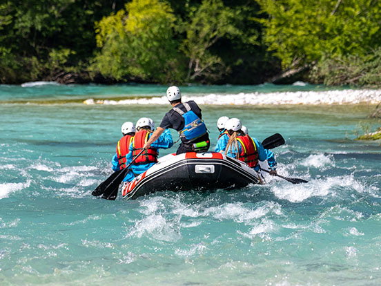Personen sitzen in einem Rafting Boot.