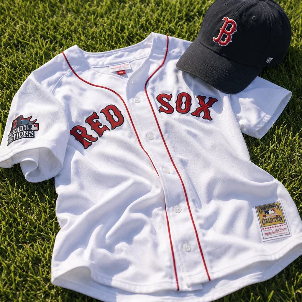 Boston Red Sox white baseball jersey with red trim and '2004 World Champions' patch, displayed with black B cap on grass.