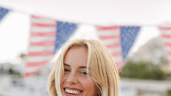 Woman smiling on the beach in front of a patriotic banner