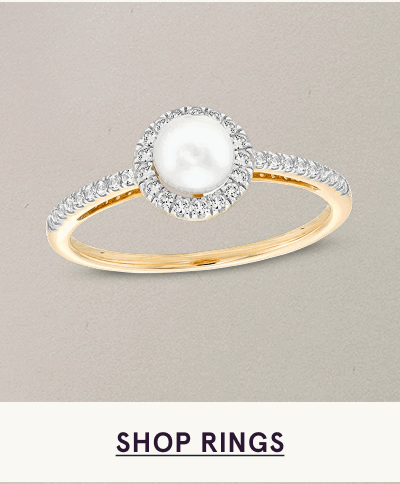 Gold band with central pearl surrounded by diamond halo, with diamonds set into the shoulders. Click here to shop rings