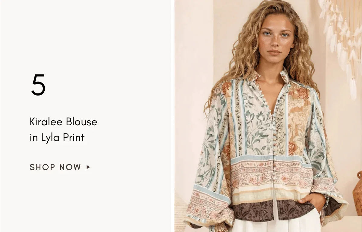 A medium shot shows a woman with wavy blonde hair wearing a long-sleeved, collared blouse with a patchwork floral and striped print in muted tones of ...