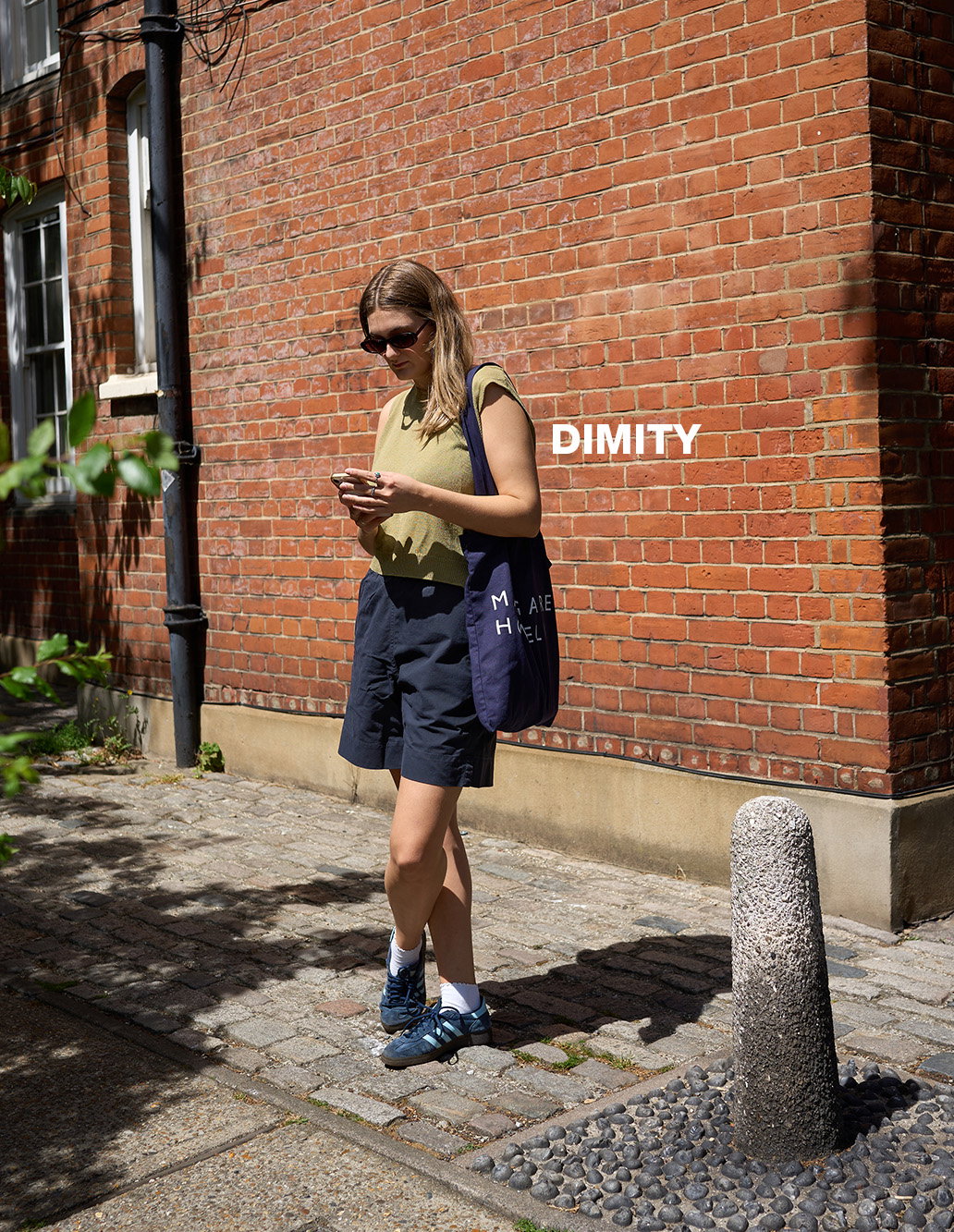 Woman wearing a green top and shorts waiting in the street.