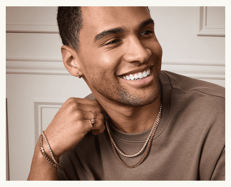 A model wearing a gold hoop earring, two gold rings, a tennis bracelet and necklace and a gold curb bracelet and necklace.