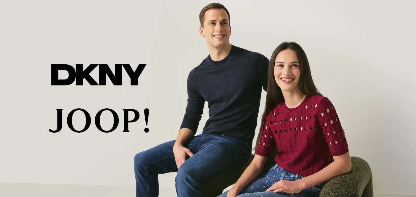 Jonge man in een zwarte trui en spijkerbroek en vrouw in een rode top en versierde spijkerbroek, zittend op een moderne, gestructureerde stoel tegen een witte muur.