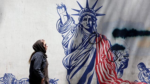 A woman in a hijab and sunglasses walks past a mural showing the Statue of Liberty with its forearm severed.
