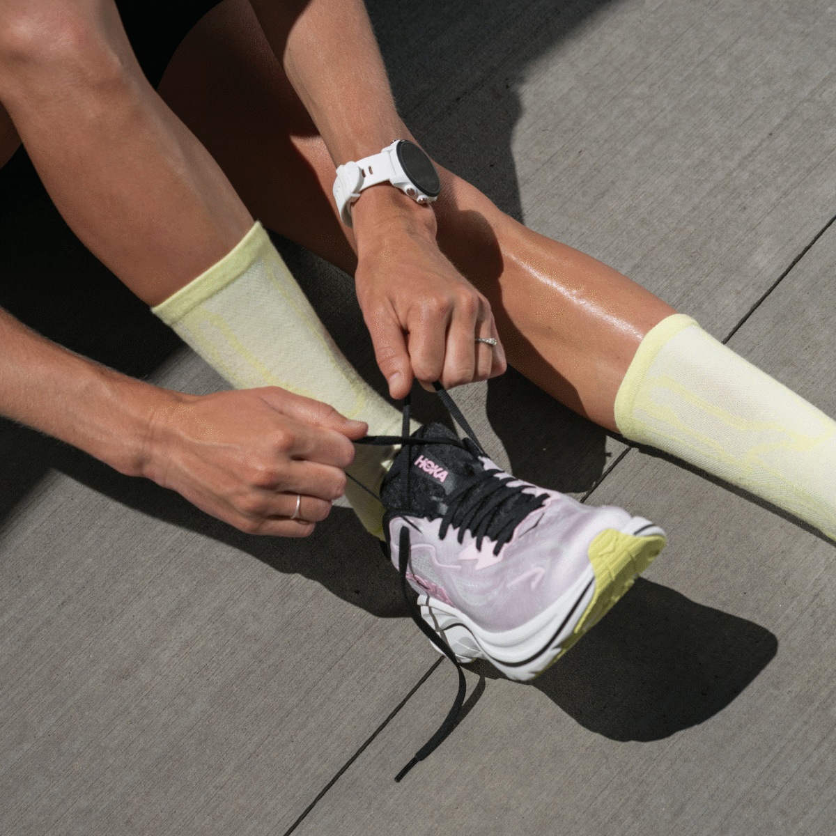 GIF showing four images: one image shows a top-down view of legs and feet wearing lilac shoes and yellow socks, with one hand tying one of the shoes; one image shows a top-down view of legs and feet, where one foot is wearing a gray shoe and a blue sock, while the other foot is wearing only a blue sock because the gray shoe is placed on the floor beside it; one image shows feet wearing green shoes and yellow socks; one image shows a side view of feet wearing lilac shoes with green socks, with one hand holding one of the socks.