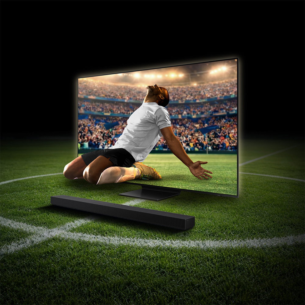 Fußballspieler vor großem Fernseher im Stadiondesign