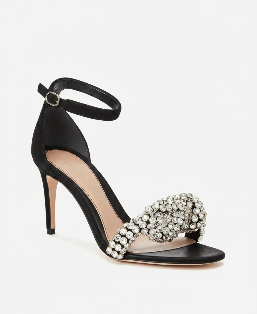 Black satin stiletto sandal with crystal-embellished bow and ankle strap.
