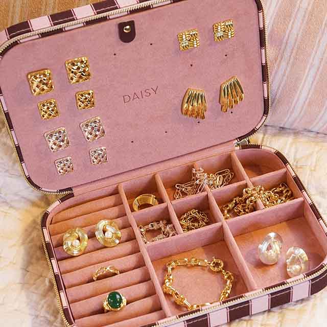 An open jewelry case displaying assorted gold earrings, rings, bracelets, and necklaces.