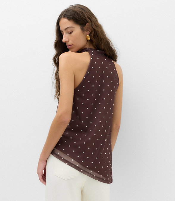 Woman looking over her shoulder wearing Mesh Polka Dot Cowl Neck Asymmetric Drape Vest in Brown Mix