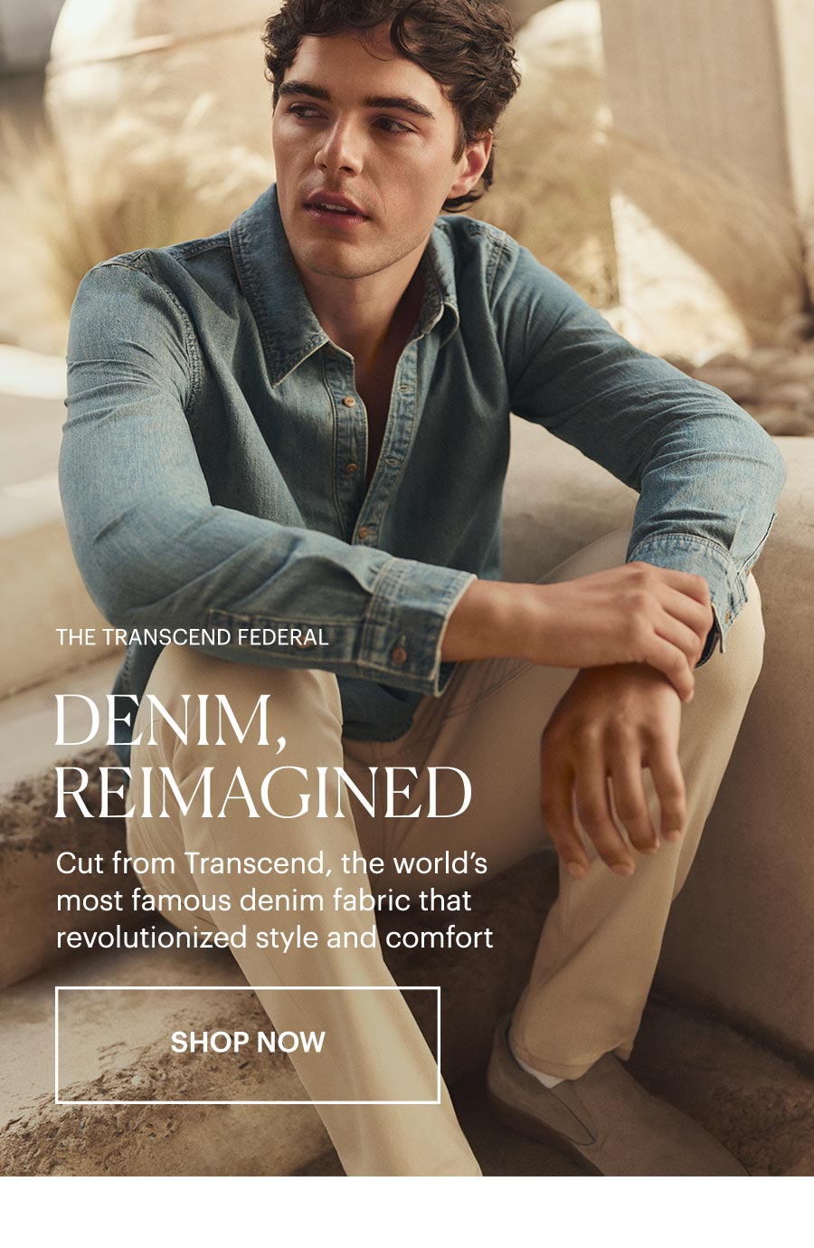 The Transcend Federal: Denim, Reimagined - Cut from Transcend, the world's most famous denim fabric that revolutionized style and comfort. Shop now. Featuring a man wearing a blue denim long-sleeved button-up with a cream pair of denim and beige suede slides, sat on a sunlit stone staircase.