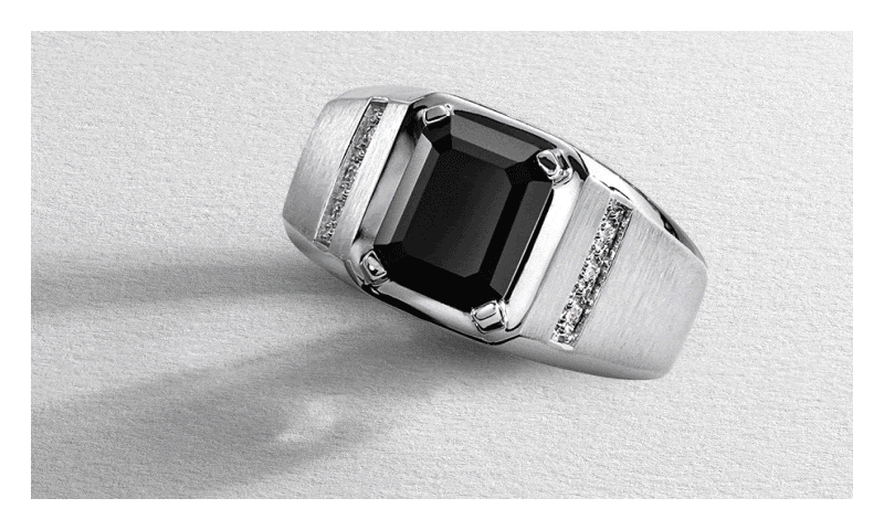 Rotating GIF featuring silver ring with black gemstone and diamonds, yellow gold gemstone earrings, and black link bracelet. 
