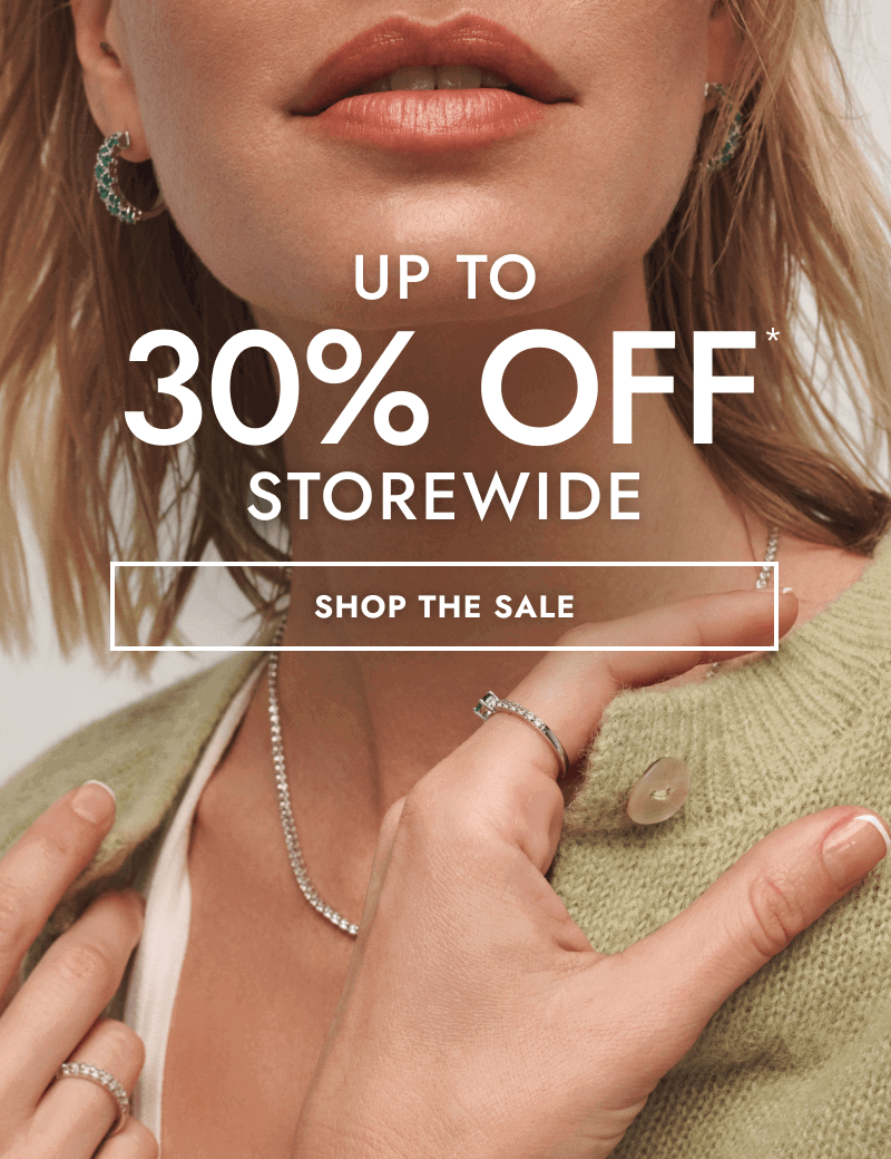 Woman wearing diamond tennis necklace, emerald earrings and fashion rings. Up to 30% Off storewide. Click shop the sale.