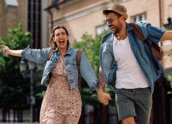 Ein fröhliches Pärchen läuft durch die Straßen. Jetzt Last-Minute-Angebote entdecken
